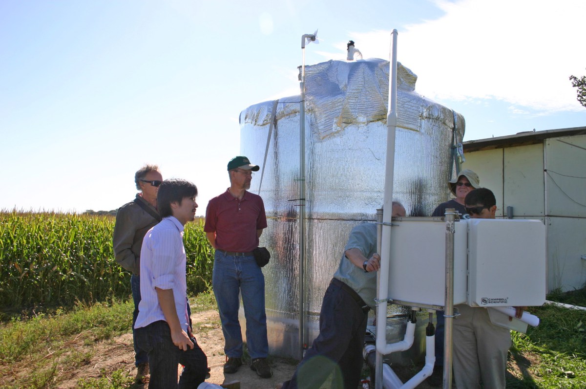 Researchers examine controls next to a large water storage tank, which supplies the bioreactor compartments with water at a stable pressure and flow rate. Credit: Michael Winikoff, BioTechnology Institute